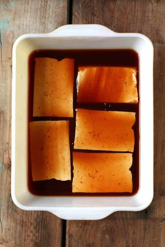 Tofu cut into slabs and marinating in a casserole dish