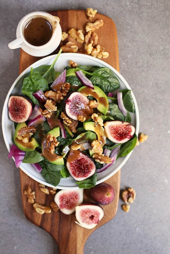 Finished salad on a wooden platter with fresh figs