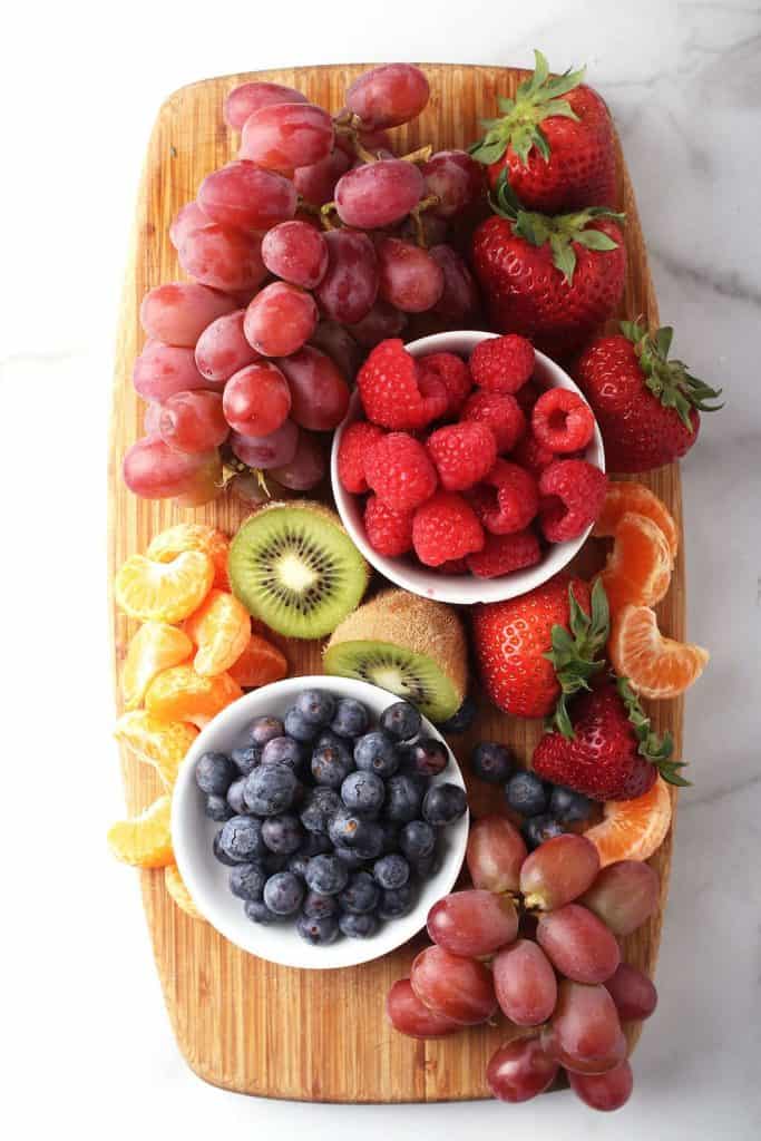 Berries and kiwi on a wooden cutting board